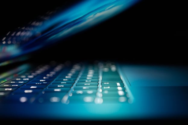 A half-open laptop glows against a dark background.